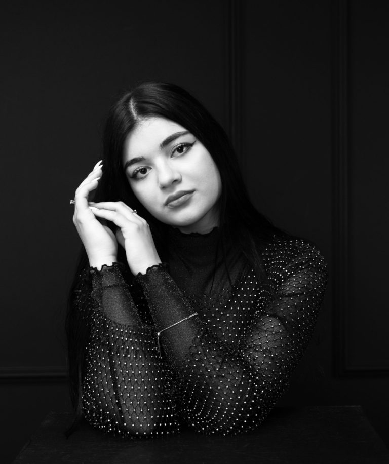 Portret feminin alb-negru al unei femei brunete, cu o expresie delicată și o privire profundă, fotografiată de Ramona Ilie.