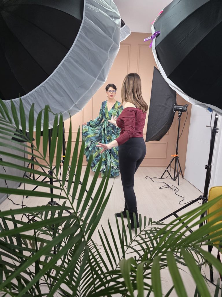 Fotografa Ramona Ilie ghidează o femeie în rochie verde în timpul unei ședințe foto pentru femei în studioul din Timișoara